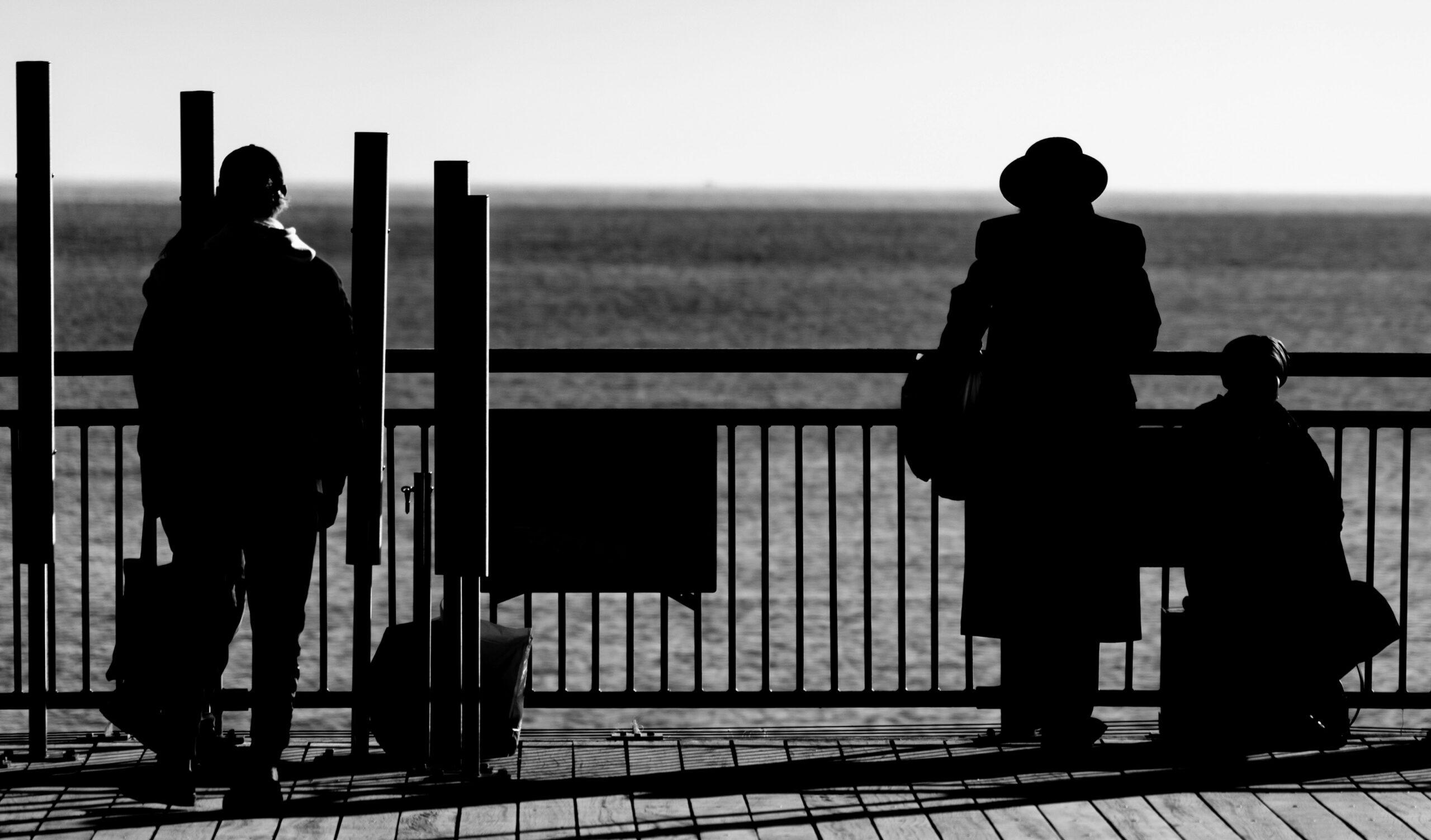 Un grupo de personas reunidas en un muelle de madera, contemplando el agua en un día soleado.